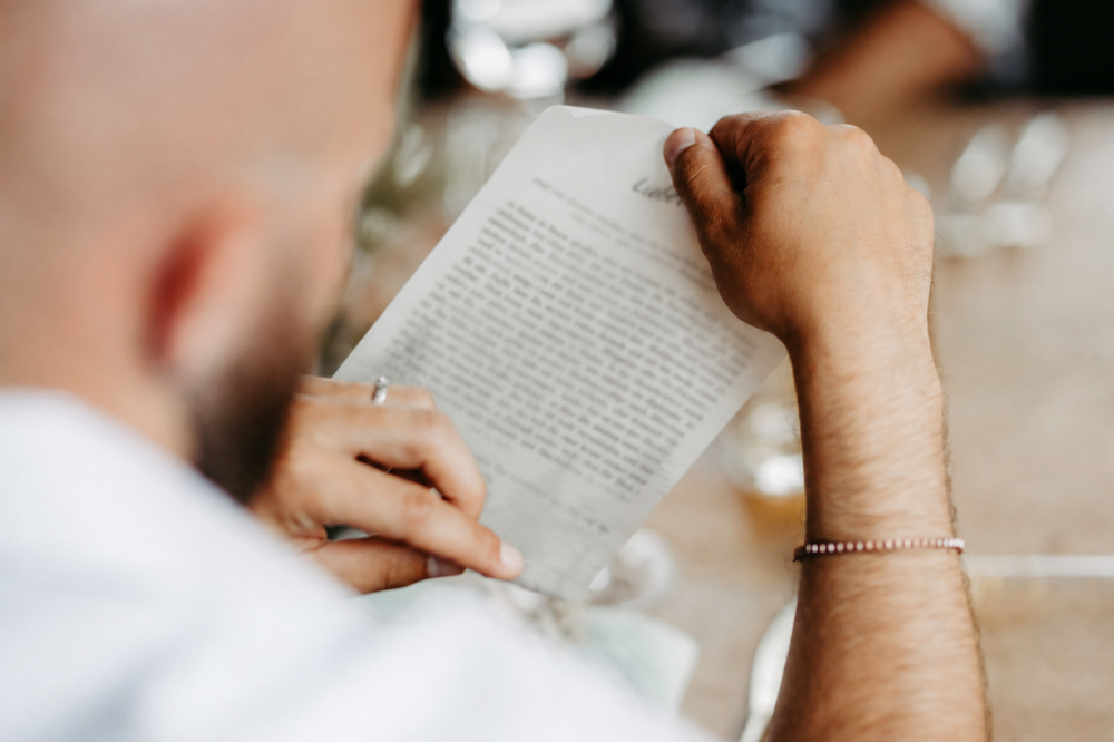 Person liest ein Dokument, Fokus auf Hände und Text. Symbol für Selbstreflexion und Persönlichkeitsentwicklung.