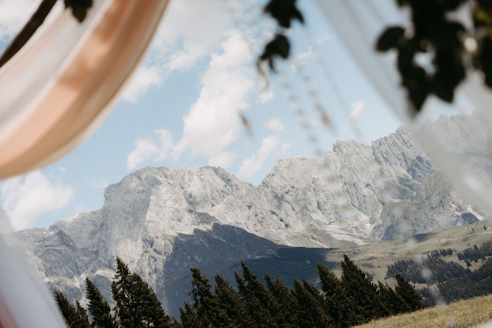 Blick auf majestätische Berglandschaft, eingerahmt von sanft fließenden Stoffen, inspiriert zu innerer Ruhe und Klarheit – Berghochzeit auf der Tiergartenalm, Mühlbach